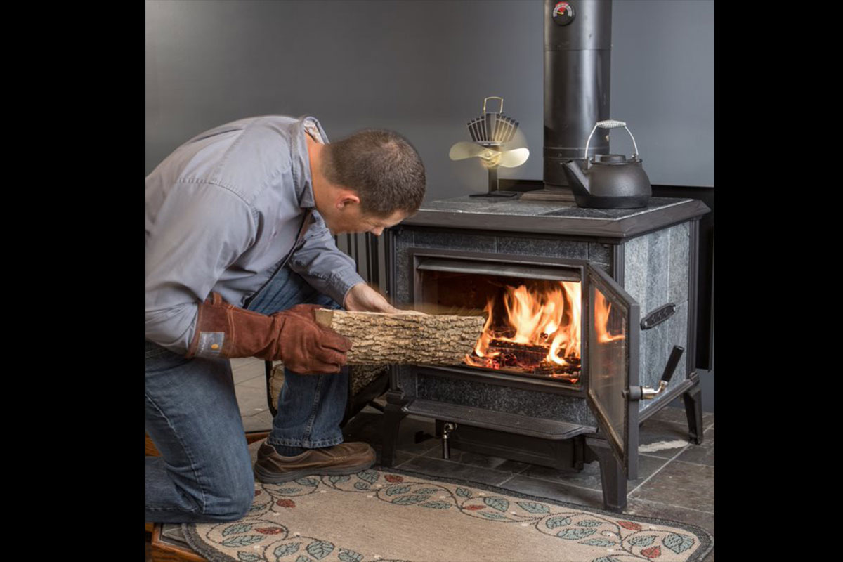 man feeding split log into fireplace